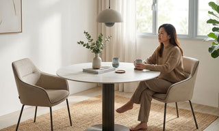 Woman seated at a 1m round dining table in a bright Singapore home with neutral chairs and soft natural light.
