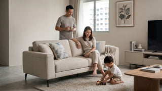 Family relaxing around a beige 3-seater sofa in a 4-room HDB living room with a coffee table and TV console.