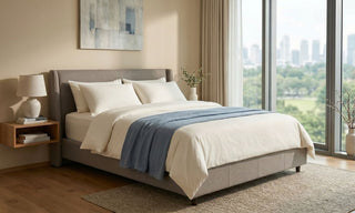 Amour-style mattress on a grey upholstered bed in a bright Singapore bedroom with city views.