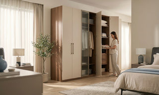 Woman organising folded clothes in an open bedroom cabinet with wood and cream wardrobe doors in a bright Singapore bedroom.
