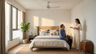 Modern Singapore bedroom with a white ceiling fan, upholstered bed, warm wood furniture, and a couple relaxing in natural daylight.