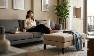 Woman relaxing on a grey sofa with a beige ottoman stool in a modern Singapore living room.