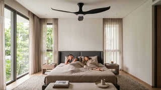 Black ceiling fan above a cosy modern bedroom with a couple resting in a bright Singapore condo home