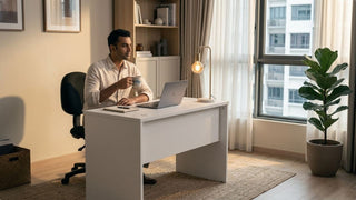 Man sitting on a black cloth office chair at a white desk in a warm Singapore home office