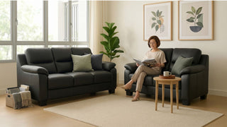 Black leather sofa set in a cosy HDB living room with neutral rug, side table and older woman reading