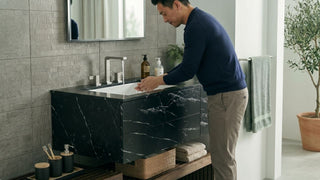 Man washing hands at a black marble wall-hung bathroom vanity with under-counter basin in a modern Singapore home