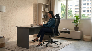 Woman working on a laptop while seated on a black mesh office chair in a cosy Singapore home office
