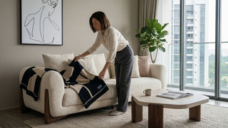 Woman styling a black patterned sofa throw blanket on a cream sofa in a modern Singapore living room