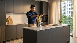 Man preparing fruit in a blender machine on a spacious kitchen island, showing convenient blending for daily household use