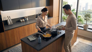 Couple using a built-in induction hob on a kitchen island in a bright Singapore home