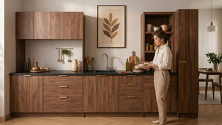Woman organising dishes beside a built-in wood kitchen cabinet with sink, drawers, and tall pantry storage