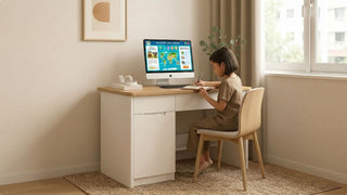 Child writing at a white and wood kids study desk with desktop computer, storage drawers, and window-side natural light