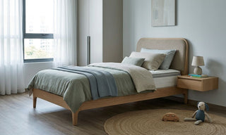 Children’s single mattress on a wooden bed frame in a calm modern Singapore bedroom with soft blue bedding