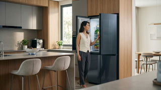 Woman checking refrigerator door clearance in a modern Singapore kitchen with wood cabinetry