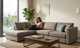 Woman reading on a grey fabric chaise sofa in a bright Singapore condo living room.