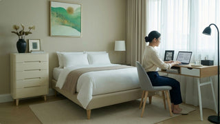 Woman working at a compact study desk in a calm bedroom with storage drawers