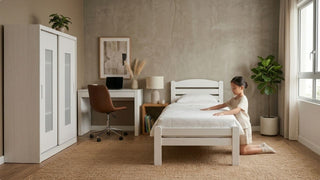 Girl making a white single bed in a compact Singapore children’s room with study desk and wardrobe