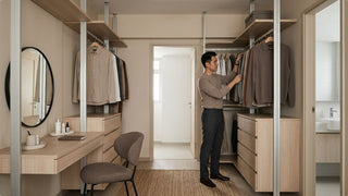 Man arranging clothes in a compact walk-in closet with modular wardrobe storage