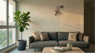 Compact wall fan above a grey sofa in a modern Singapore living room with warm natural light