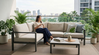 Contemporary outdoor furniture on a Singapore balcony with a beige sectional sofa, coffee table, plants, and city views.