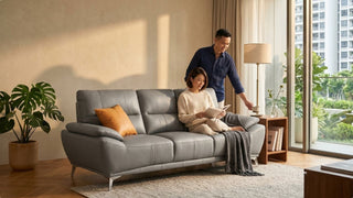 Couple relaxing on a grey leather sofa in a modern Singapore living room with warm natural light and balcony view