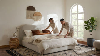 Couple making a queen bed in a bright modern bedroom with soft neutral decor