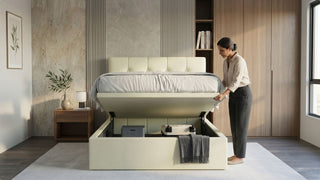 Woman opening a cream fabric storage bed with gas lift in a modern Singapore bedroom with built-in wardrobe