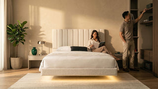 Couple styling a cream floating platform bed in a modern Singapore bedroom with built-in storage and warm natural light