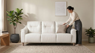 Woman arranging cushions on a cream leather sofa in a warm modern Singapore home