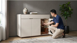 Man checking the storage compartment of a cream sideboard with glass display in a modern living room