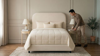 Man styling a bedside table beside a cream upholstered bed frame in a modern Singapore bedroom