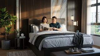 Couple reading on a dark storage bed frame in a cosy Singapore bedroom with warm wood wall panels