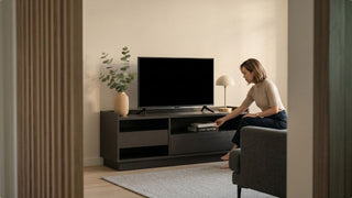 Woman organising storage on a dark TV console in a modern BTO flat living room