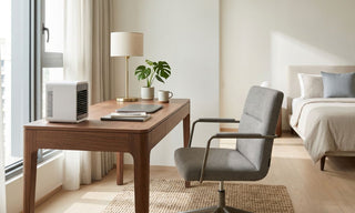 Desktop aircon on a wooden work desk in a bright Singapore bedroom home office with laptop, chair and neutral bedding.