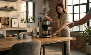Woman using a drip coffee machine in a warm home kitchen before buying the right model for Singapore homes.