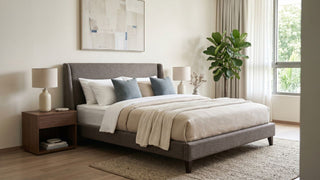 Fabric bed frame in a neutral Singapore bedroom with wooden bedside tables, soft bedding, rug, and natural window light.