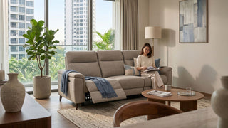 Fabric recliner sofa in a bright Singapore condo living room with neutral decor, indoor plants, and a woman reading.
