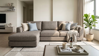 Grey fabric sectional sofa in a bright Singapore living room with fabric cleaner on the coffee table.