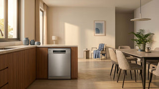 Freestanding dishwasher in a warm open-plan Singapore kitchen beside a dining area with neutral furniture.
