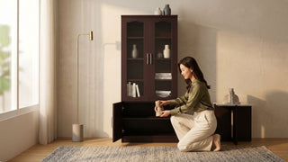 Woman styling vases inside a dark wood glass display cabinet in a warm modern Singapore home
