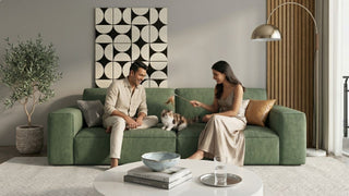 Couple playing with a cat on a green sofa in a modern Singapore home with neutral decor