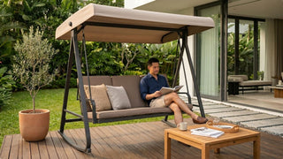 Grey canopy outdoor swing on a wooden garden deck with cushions, coffee table, and greenery