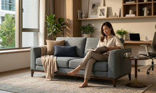 Woman reading on a grey fabric office sofa in a warm Singapore home workspace