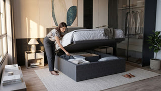 Woman arranging items inside a grey lift up storage bed with gas lift in a modern Singapore bedroom