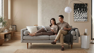 Couple relaxing on a grey sofa in a prestige-style Singapore living room with warm neutral decor