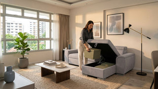 Woman organising boxes inside a grey sofa with storage in a bright Singapore HDB living room