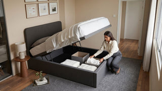 Woman organising towels inside a grey storage bed in a compact HDB bedroom with wardrobe and clear walkway space