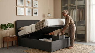 Woman organising linens inside a grey lift bed frame with under-bed storage in a stylish Singapore bedroom