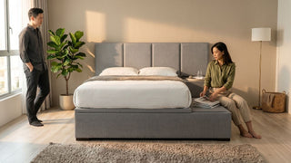Grey upholstered platform bed with side bench in a bright Singapore bedroom with couple and warm natural light