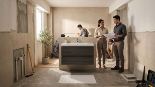 Couple checking bathroom renovation plans as contractors install tiles and vanity fittings in an HDB bathroom